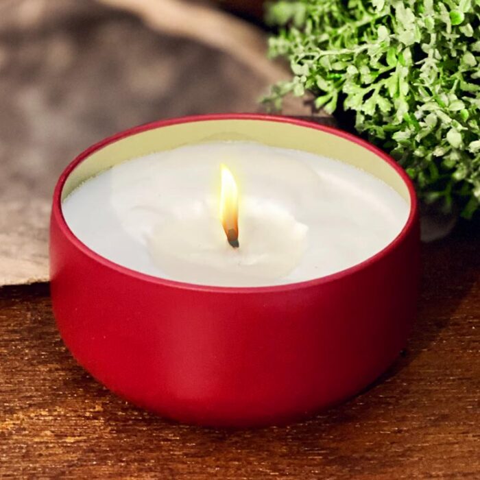 A burning candle in a red tin