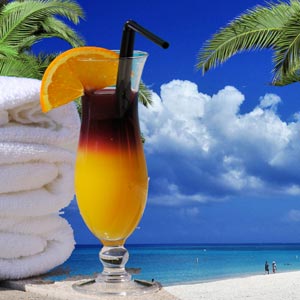 Tropical drink next to towels on a beach